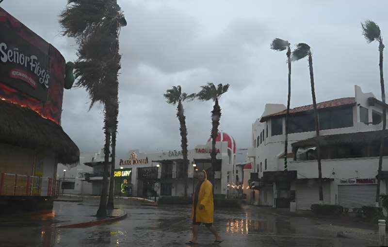 A man walks along a street in Cabo San Lucas, Mexico, as rain and wind gusts from Hurricane Hilary reach the area, on August 19,