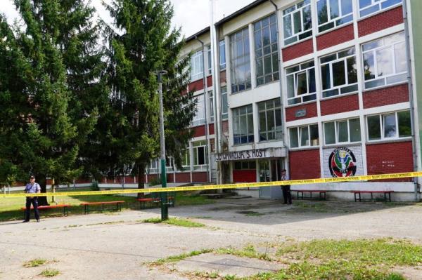 Police officers stand guard outside the building of a high school where a man opened fire killing three staff members